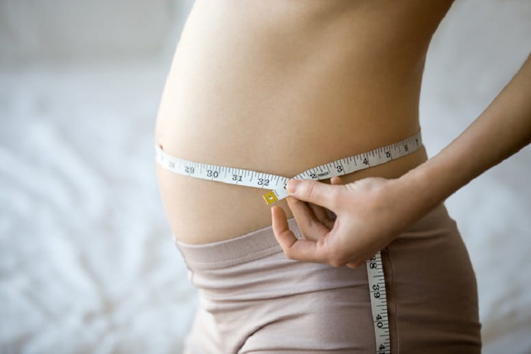 pregnant woman measuring belly