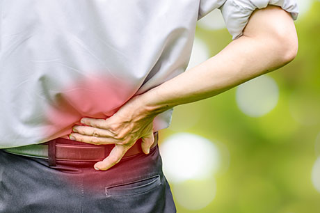 Person holding lower back in pain