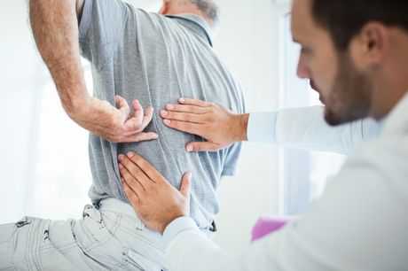 Doctor examines patient for back pain. 