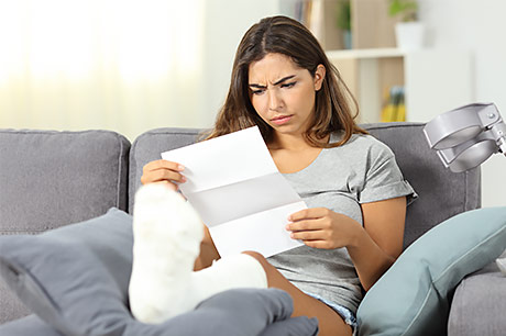 A confused young woman reviews her recent medical bills.