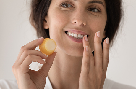 A woman applying lip balm.
