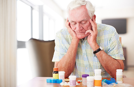 Senior man sitting and looking at his medication